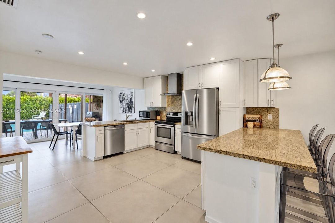 Kitchen featuring white cabinetry, stone countertops, stainless steel appliances, recessed lighting, and tile flooring