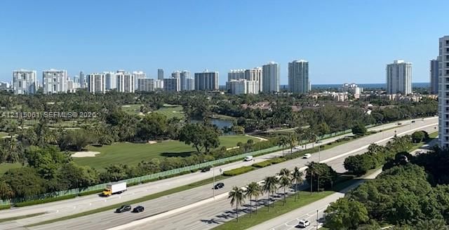 Panoramic urban skyline featuring high-rise buildings, expansive golf course grounds, mature landscaping, and a coastal horizon