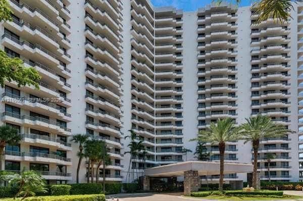 High-rise exterior featuring private balconies, architectural terraced facade, stone-clad porte-cochère, and manicured landscaping