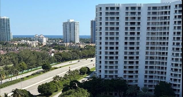 High-rise residential exterior featuring a white concrete facade, uniform recessed balconies, and mature palm trees