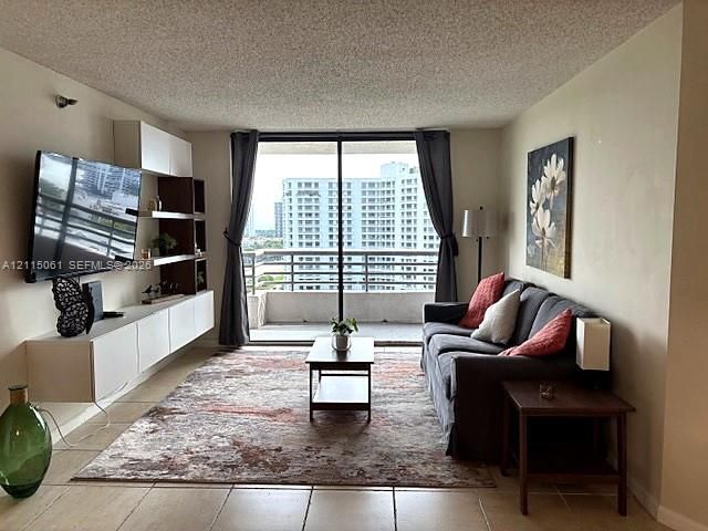 Living area featuring ceramic tile flooring, built-in wall-mounted cabinetry with integrated shelving, and large floor-to-ceiling sliding glass doors opening to a private balcony