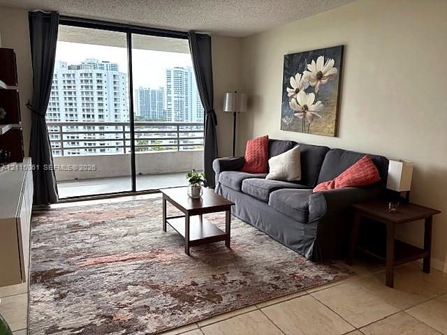 Living area featuring large format tile flooring and floor-to-ceiling sliding glass doors opening to a balcony with metallic railing
