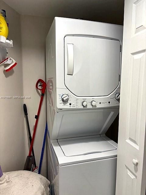 Stacked laundry unit housed within a closet featuring white panel doors
