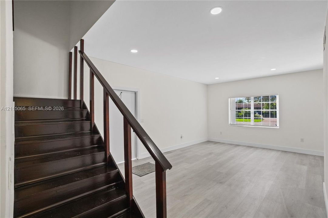 Staircase featuring dark wood-finish treads and railings, recessed ceiling lighting, and neutral wood-finish flooring throughout