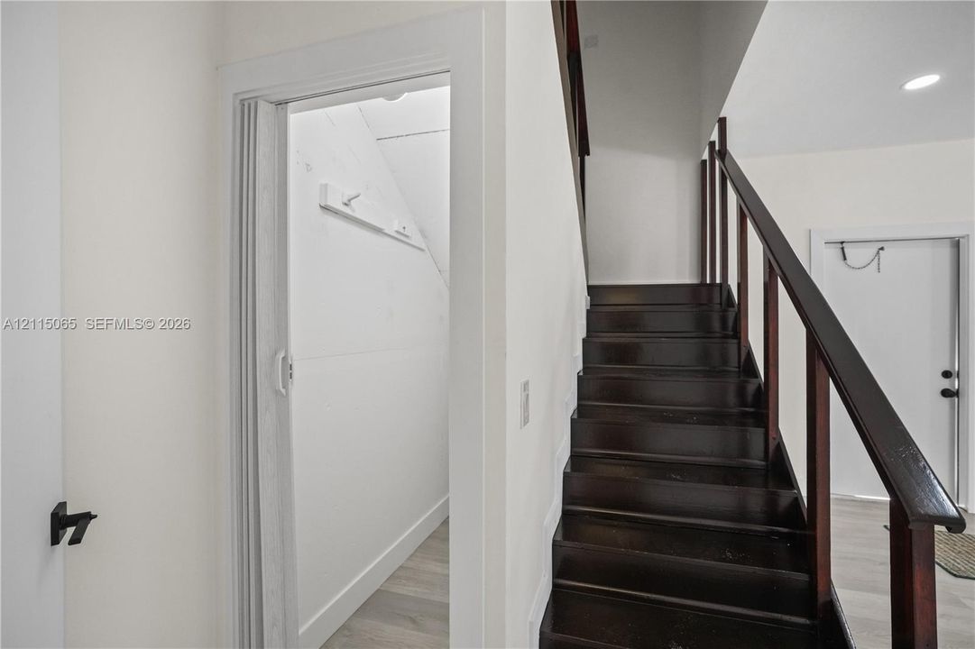 Dark wood staircase with an open-railing banister and neutral-toned wood-finish flooring