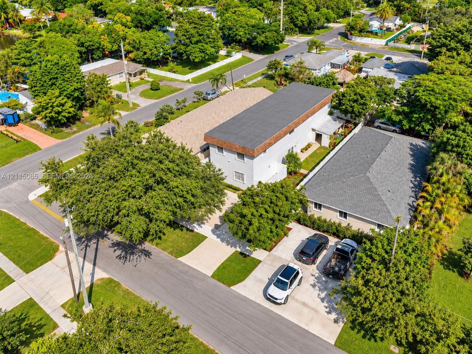 Multi-structure property featuring concrete driveways, mature canopy trees, low-slope roofing, and exterior masonry walls