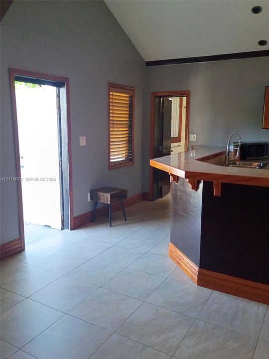 Vaulted ceiling, ceramic tile flooring, and bar-height counter with wood trim