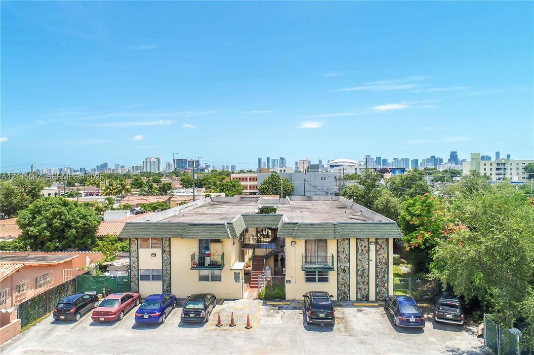 Two-story multifamily property featuring decorative stone exterior accents, individual unit balconies, and dedicated surface parking