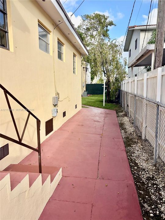 Side exterior featuring a concrete walkway, stucco wall finish, and a metal staircase with railing