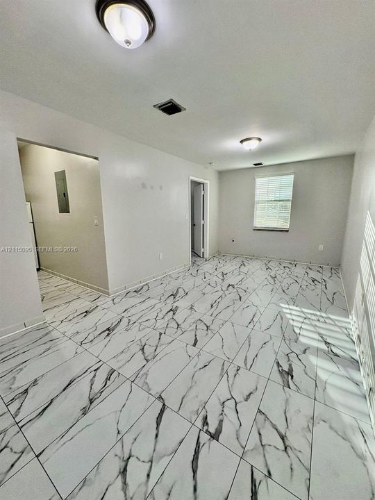 Large-format tile flooring featuring high-contrast vein patterning, dual flush-mount ceiling light fixtures, and neutral wall tones