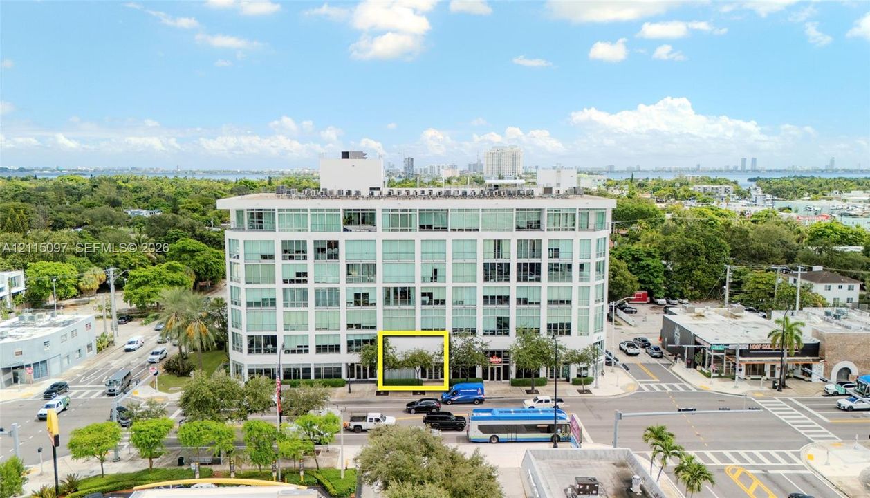 Multi-story glass-facade building featuring expansive window panels, integrated ground-level landscaping, and a corner location with street-level accessibility