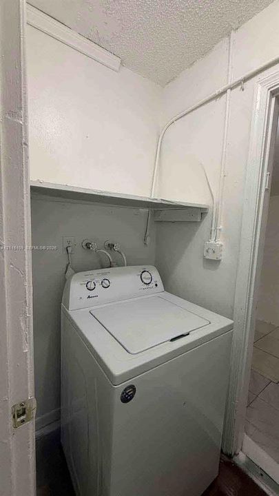 Laundry alcove featuring a built-in overhead shelf and dedicated water and electrical hookups
