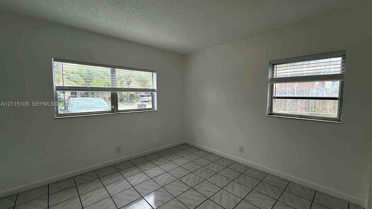 Interior room featuring large-format diagonal tile flooring, smooth wall finishes, and two horizontal windows