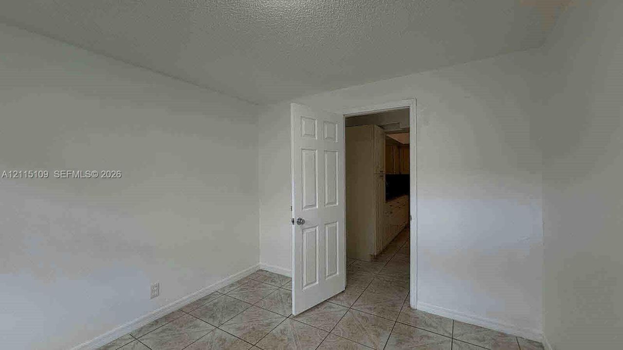 Interior space featuring neutral wall tones, large-format tile flooring, and a classic six-panel interior door