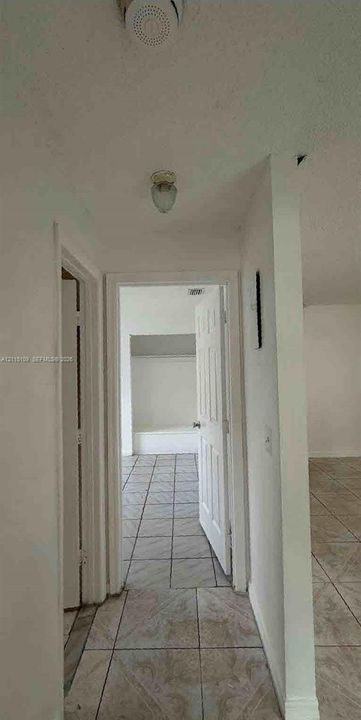 Interior hallway featuring ceramic tile flooring, neutral wall finishes, flush-mount lighting, and solid-core paneled doors