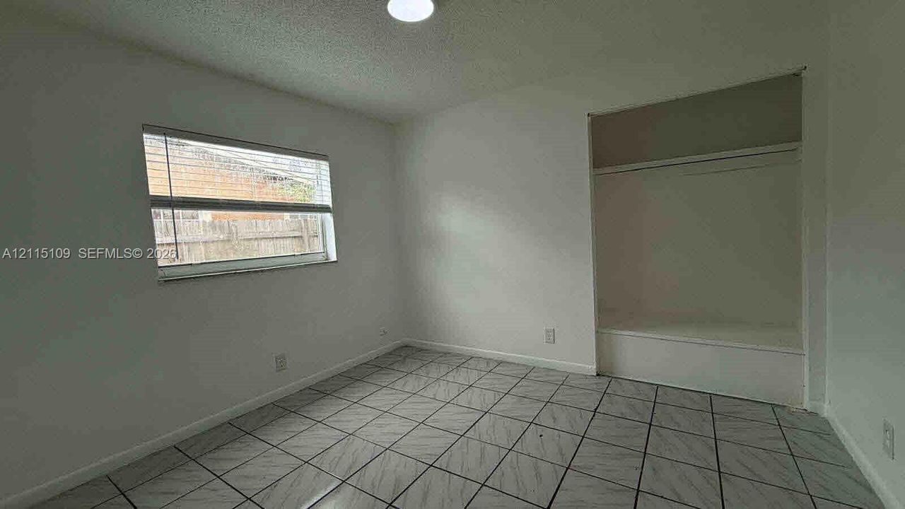 Room featuring neutral wall finishes, tile flooring, a horizontal window, and a built-in recessed storage alcove