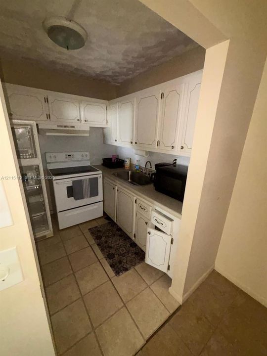 Kitchen featuring white cabinetry, tile flooring, and an integrated range hood