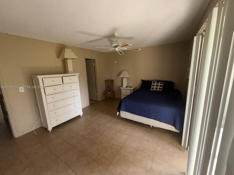 Spacious room featuring neutral wall paint, tile flooring, and a ceiling-mounted fan with integrated lighting