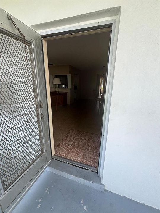Metal security screen door featuring an integrated diamond-pattern mesh, installed in a white-trimmed doorway with tiled entry flooring