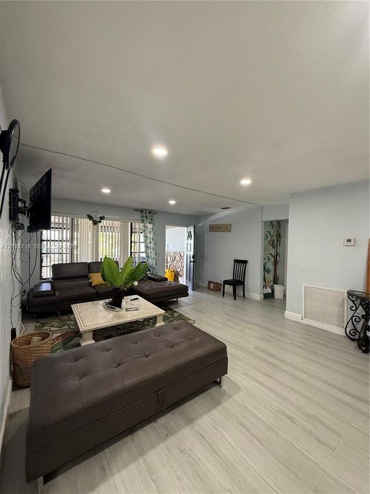 Living space featuring wood-finish flooring, recessed lighting, and large windows with vertical blinds