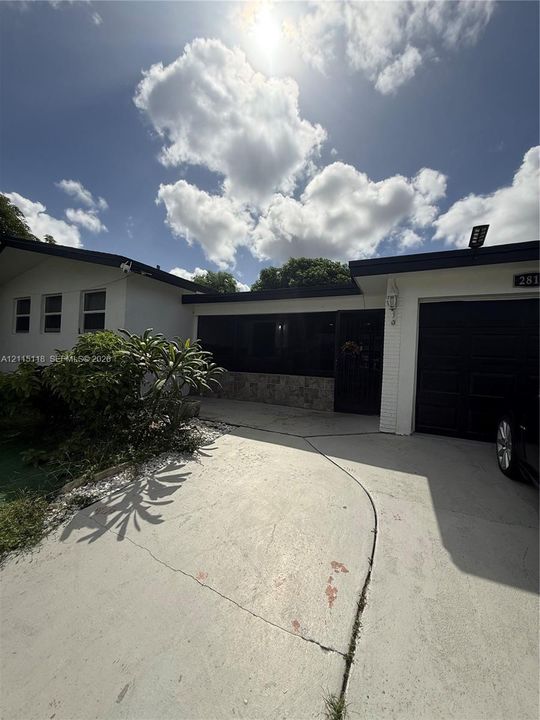 Single-story exterior featuring white masonry facade, stone accent detailing, dark-toned trim, and an attached garage