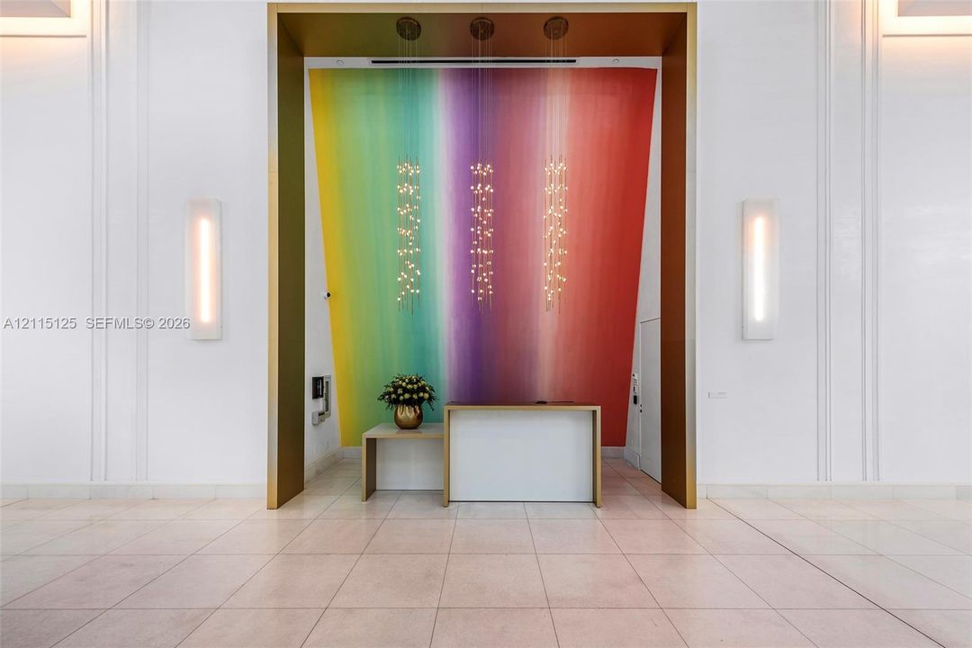 Grand foyer entrance featuring a gold-toned recessed alcove, large-scale gradient wall mural, trio of suspended pendant light fixtures, and polished tile flooring