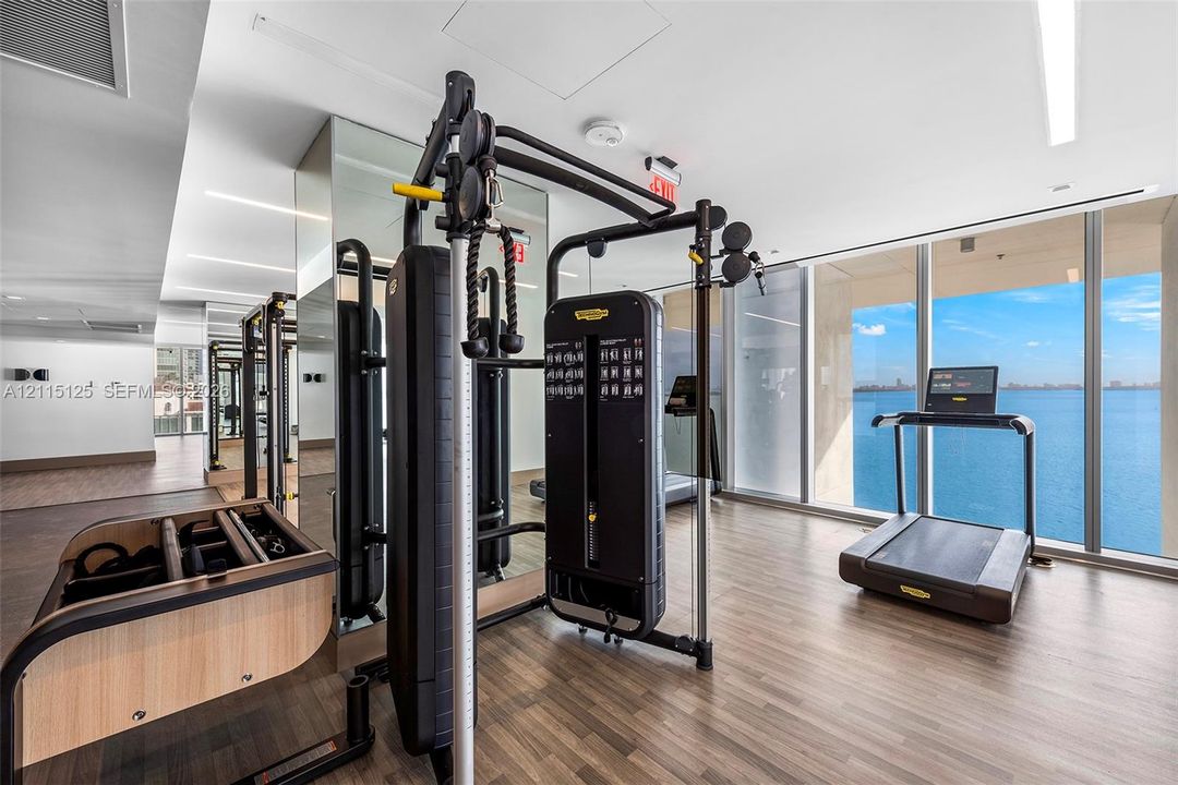Open-concept interior featuring high ceilings with recessed LED perimeter lighting, flat-panel cabinetry, built-in stainless steel double ovens, and polished stone flooring