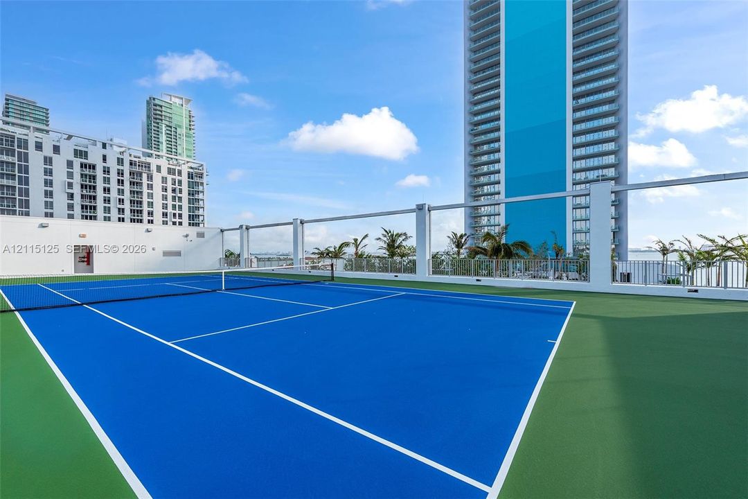 High-rise exterior featuring a striking turquoise accent panel, floor-to-ceiling glass windows, and private glass-railed balconies