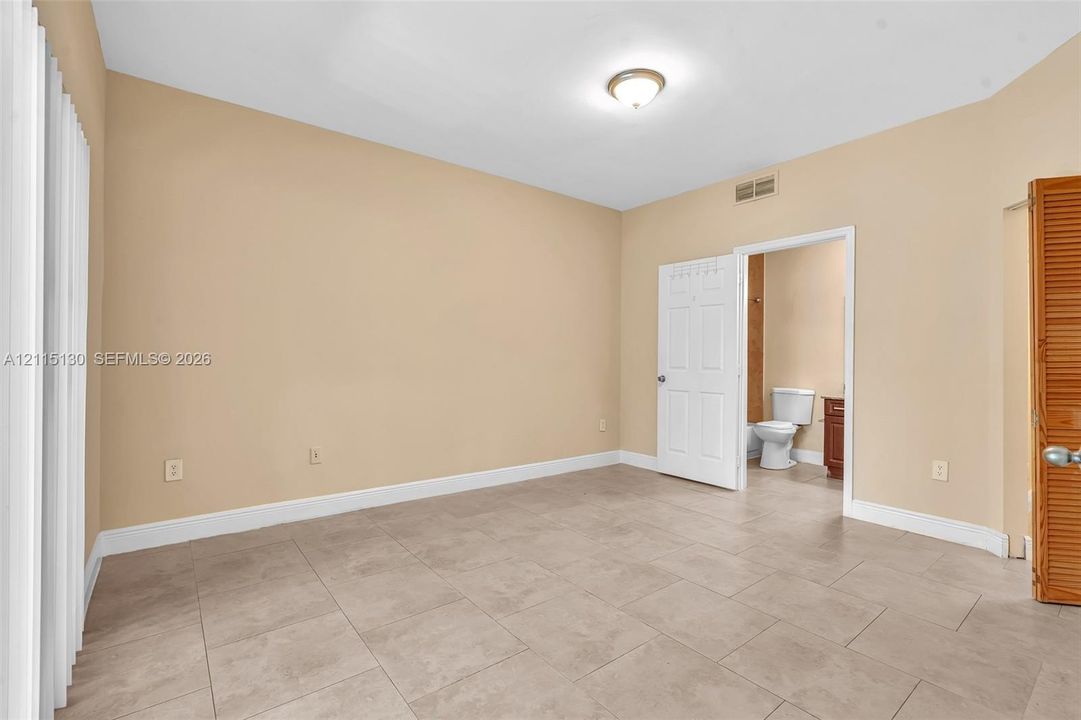 Neutral-toned interior room featuring large-format ceramic tile flooring, a six-panel interior door, and a wooden bi-fold door