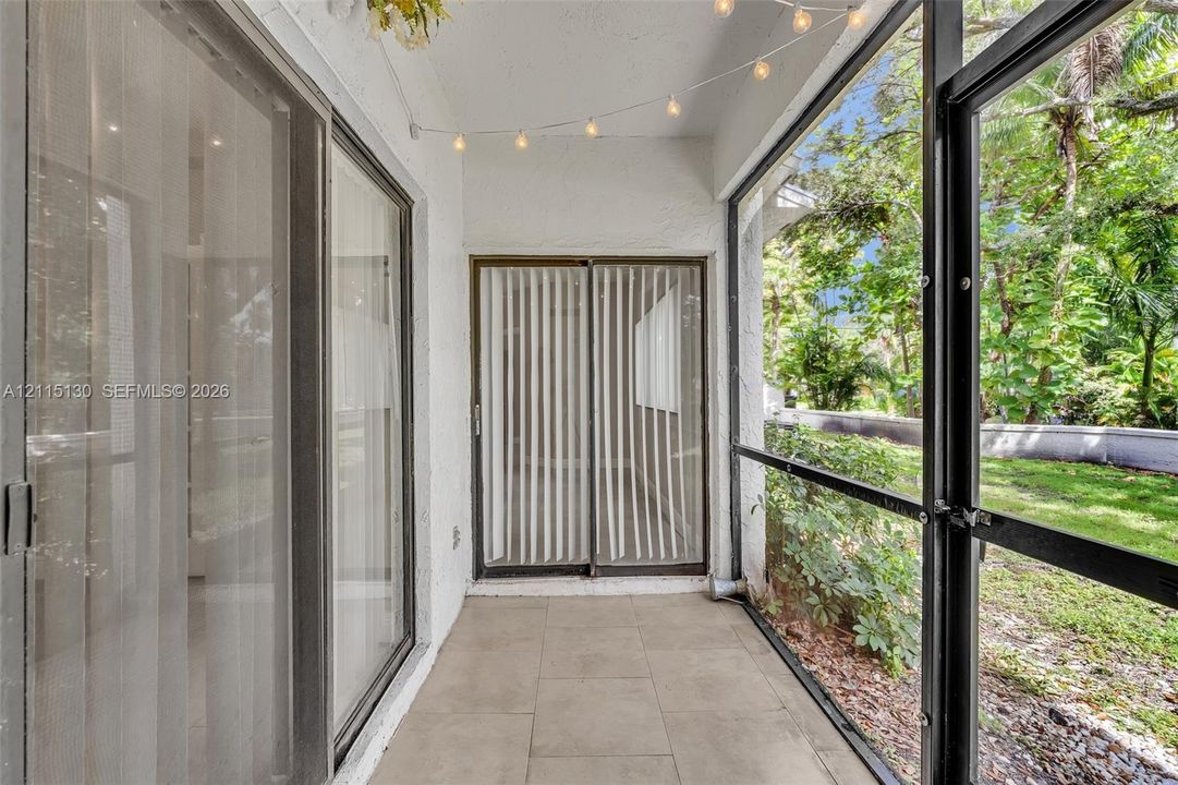 Screened-in patio featuring tile flooring, sliding glass door access, and exterior metal framing