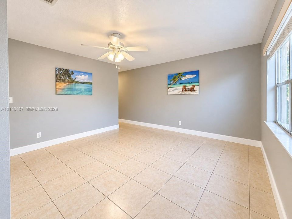 Interior space featuring neutral wall paint, tile flooring, white-finish ceiling fan with integrated lighting, and a multi-pane window