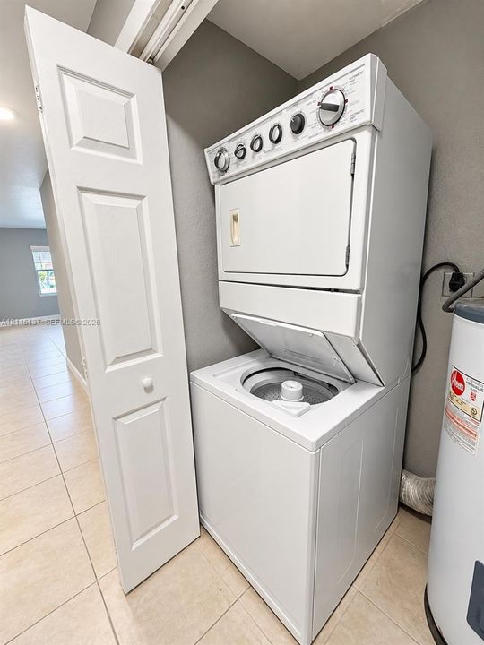 Stacked white laundry unit with top-loading washer, integrated dryer, and bi-fold closet door