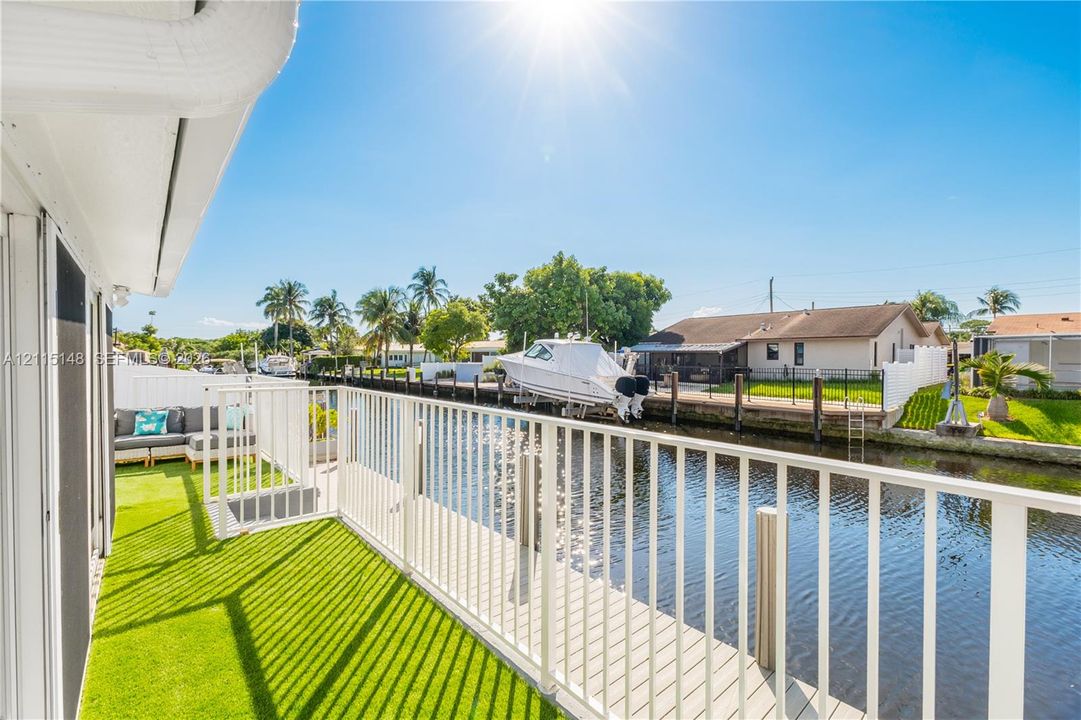 Waterfront deck featuring synthetic turf flooring, vertical baluster railing, and direct water access