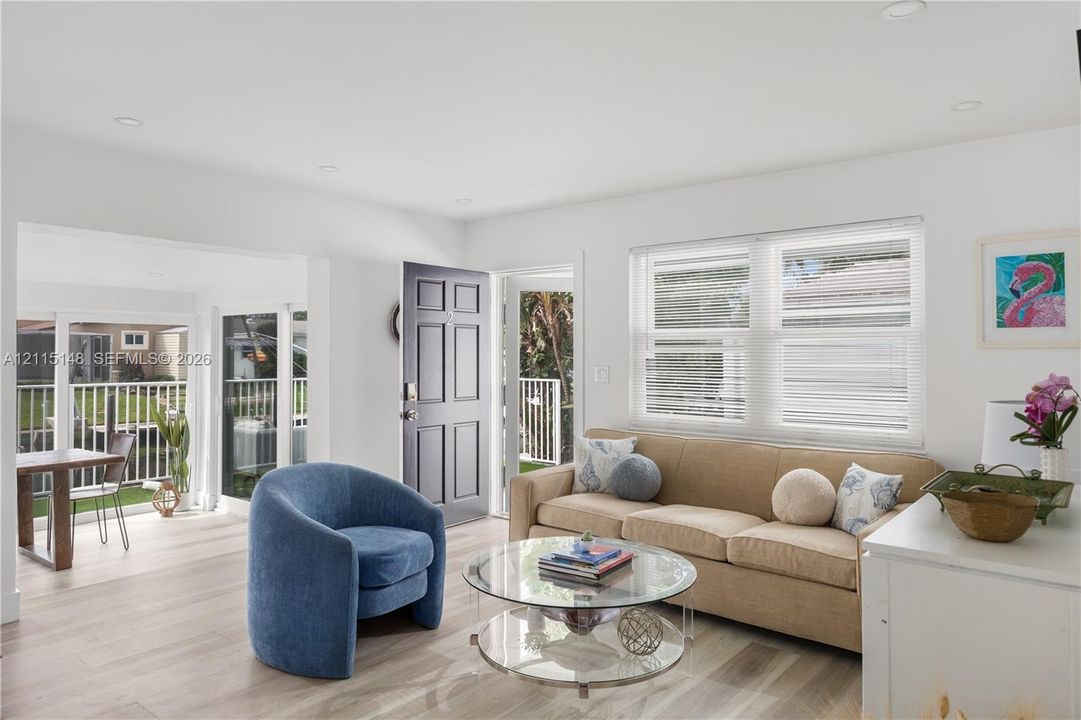 Living area featuring wood-finish flooring, recessed lighting, double-hung windows with blinds, and a multi-panel entry door