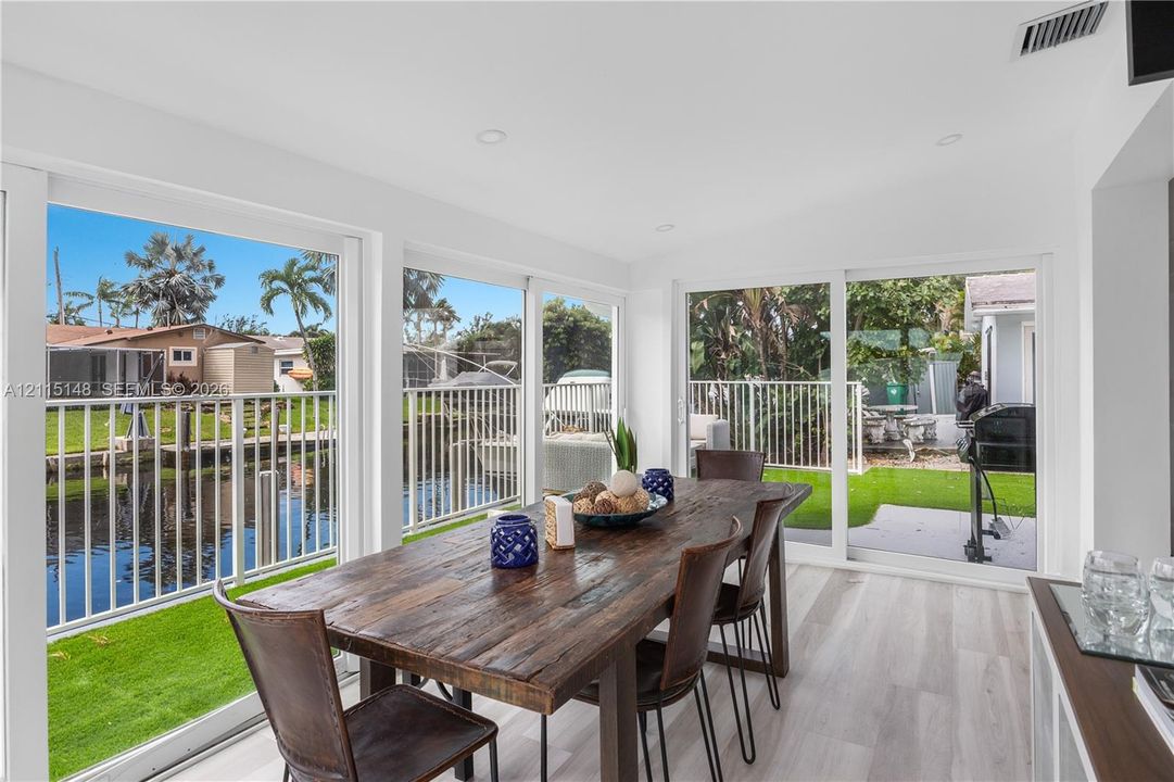 Sunroom featuring wood-finish flooring, recessed lighting, and multiple sliding glass doors opening to a waterfront canal setting