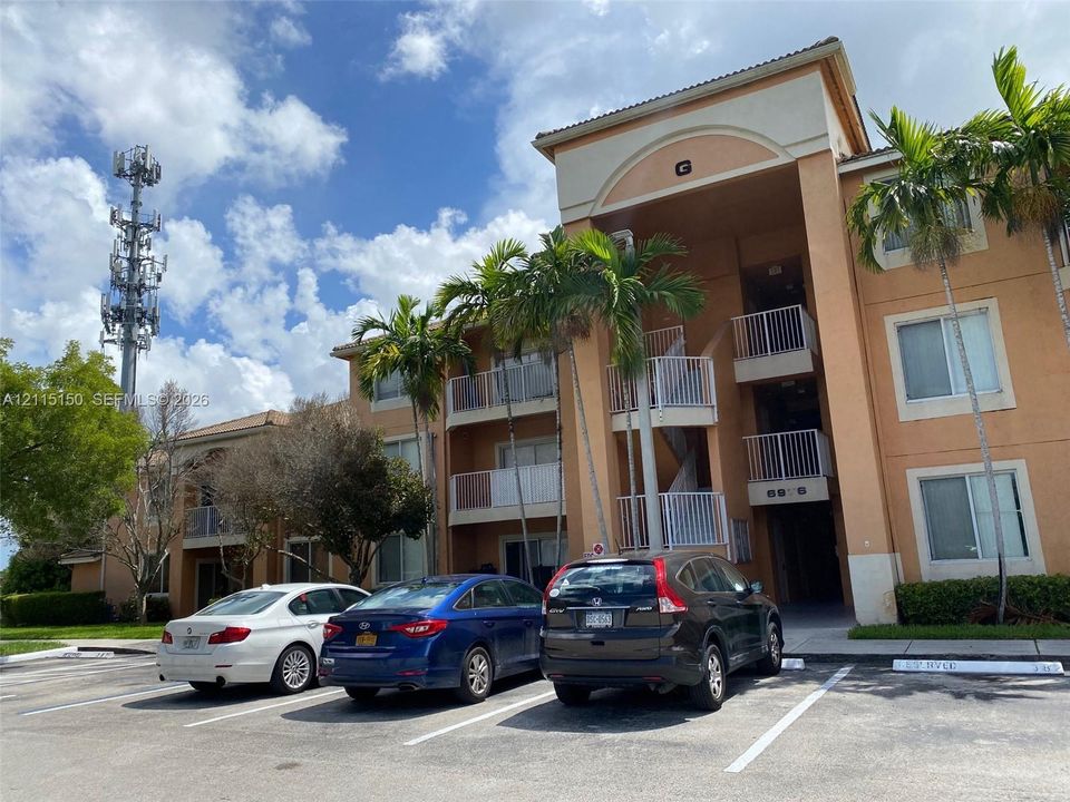 Multi-story stucco exterior featuring arched architectural detailing, private balconies with metal railings, and mature palm landscaping