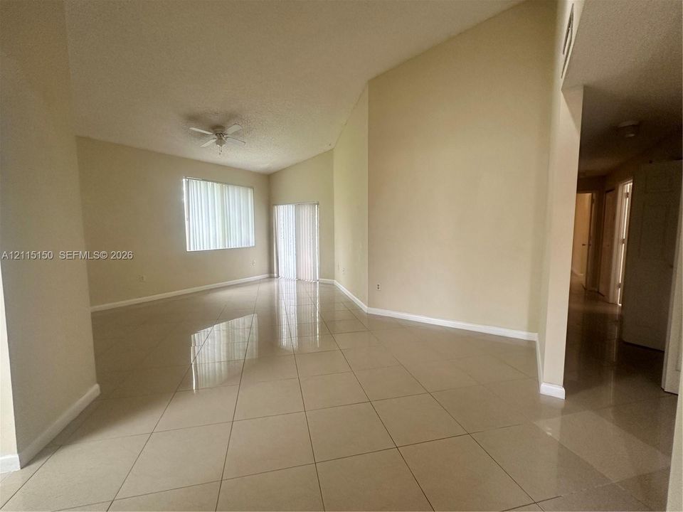 High vaulted ceilings, neutral ceramic tile flooring, and a ceiling fan