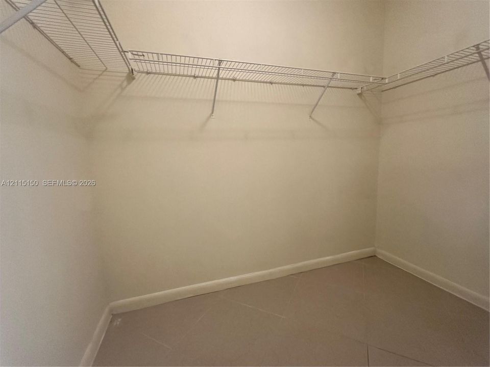 Walk-in storage space featuring neutral tile flooring and multi-level white wire shelving
