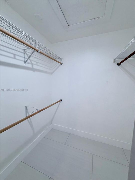 Walk-in closet featuring large-format tile flooring and tiered wire shelving with wood-finish rods