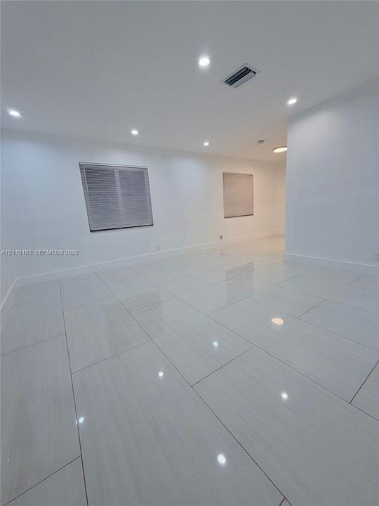 Large-format white tile flooring, recessed ceiling lighting, and crisp neutral wall finish