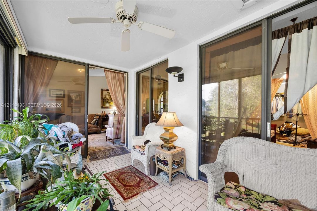 Enclosed patio featuring ceramic tile flooring, a ceiling-mounted fan, and wall-mounted light fixtures with large glass sliding doors