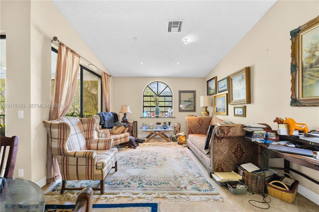 Living area featuring an arched window, sliding glass door, recessed lighting, and tile flooring