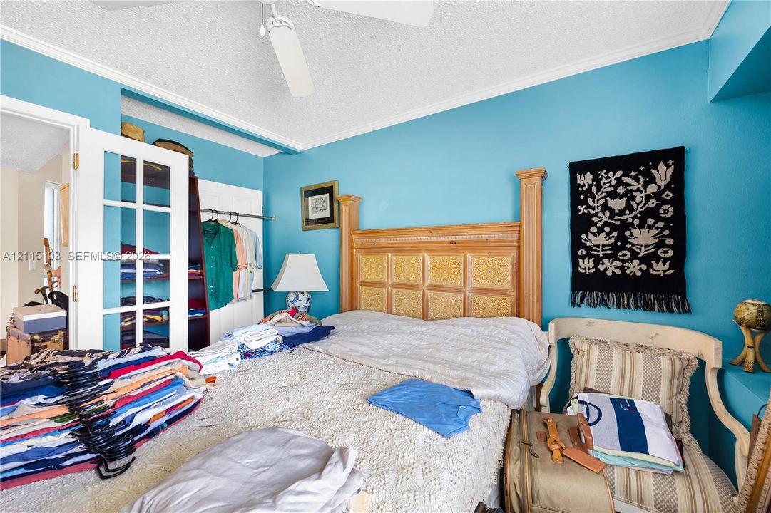 French-door closet entry featuring white trim, ceiling-mounted paddle fan, and crown molding