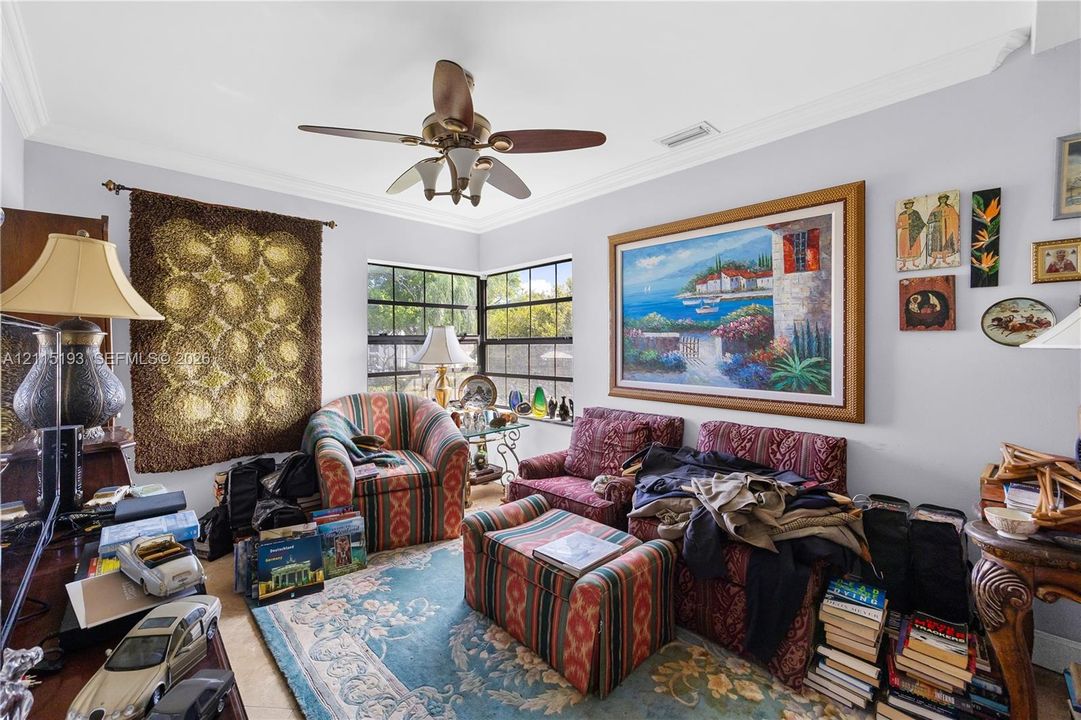 Living area featuring crown molding, multi-pane windows, and a ceiling fan with integrated lighting