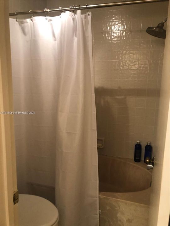 Bathroom featuring a soaking tub, square-tile wall surround, and a wall-mounted shower head