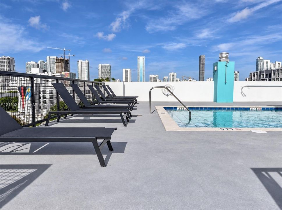 Rooftop terrace featuring an outdoor pool with a metal handrail, concrete decking, and a metal grid perimeter railing
