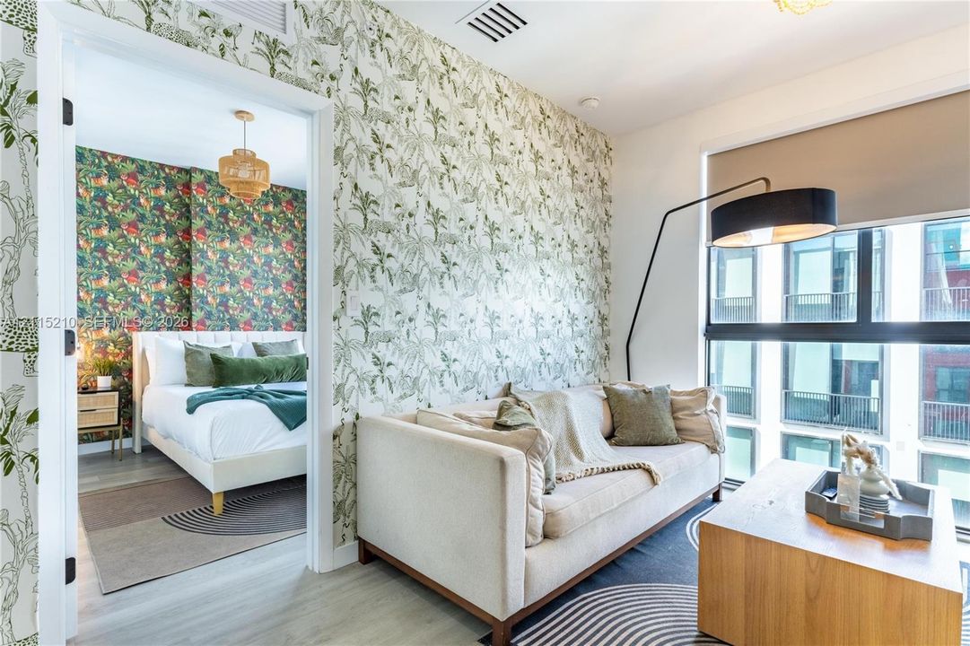 Interior space featuring large-format windows with roller shades, botanical patterned wallpaper, and light-toned wood-finish flooring