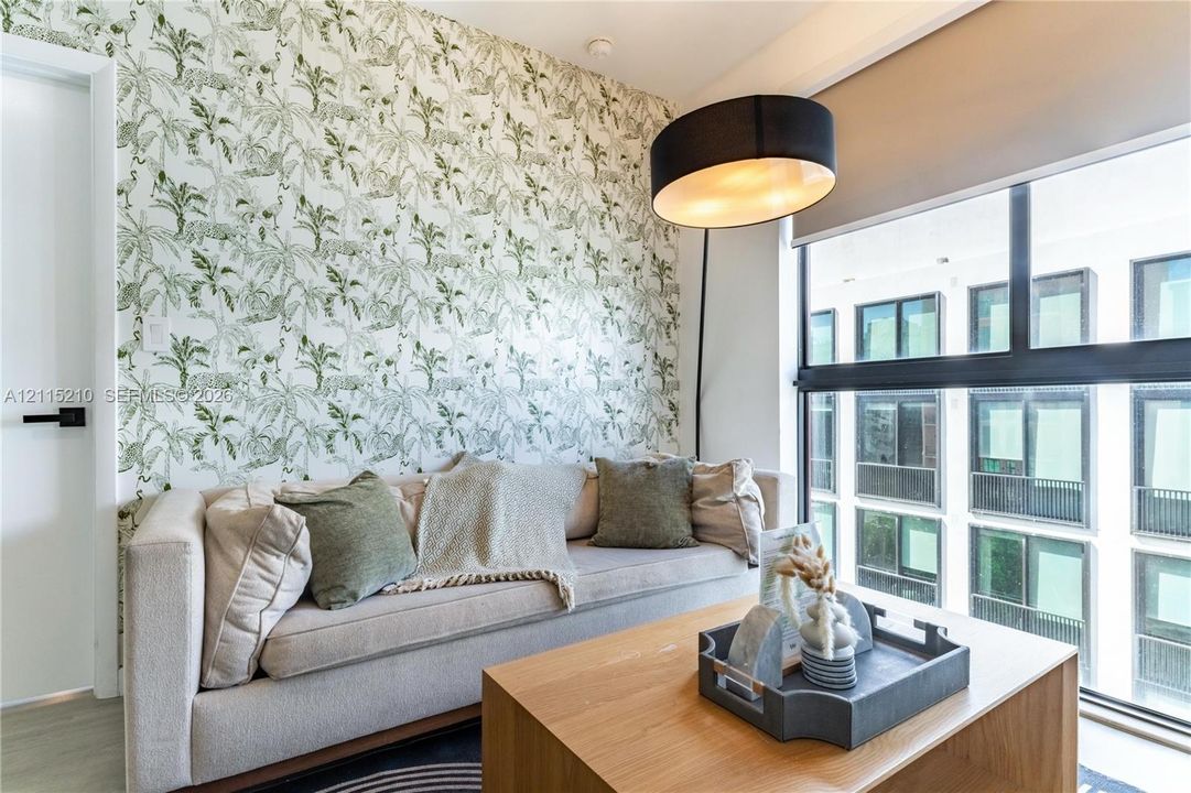Statement wall featuring patterned wallpaper, expansive multi-pane window, and modern black hardware