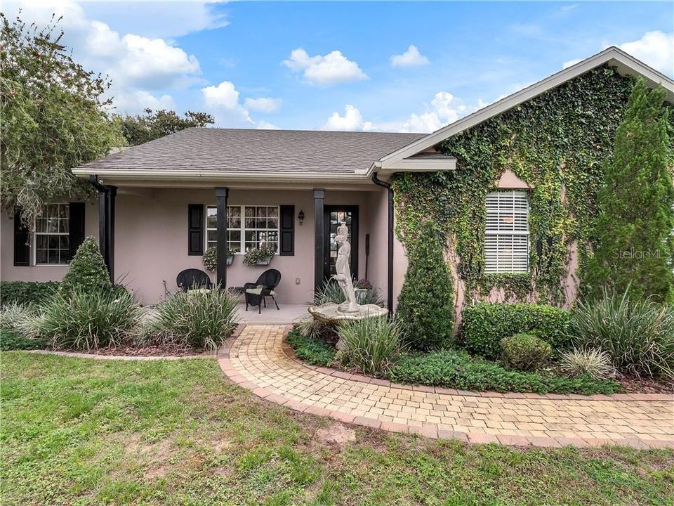 Main House with beautifully paved sidewalk leading to sitting area outside the front door.