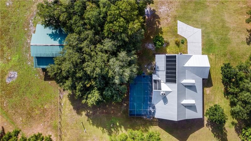 Aerial view of house with solar panels for heating pool and barn